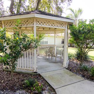 A charming garden gazebo with patio furniture and surrounding greenery.