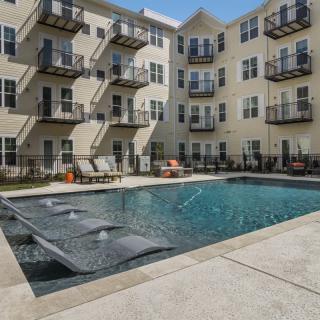 A sunny day at a residential complex featuring a swimming pool and balconies.