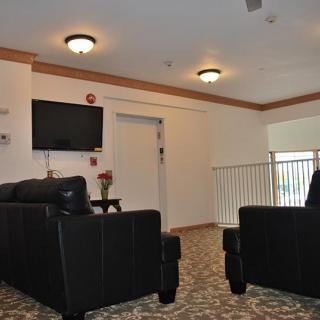 A modern living room with black sofas and a wall-mounted TV.