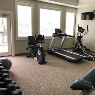 A home gym equipped with a treadmill, elliptical, stationary bike, and dumbbells.