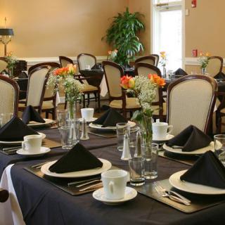 An elegantly set dining room with black napkins and floral centerpieces.