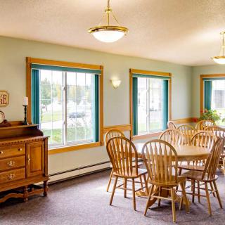A bright dining room with wooden furniture and large windows.