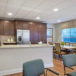 A modern kitchen and dining area featuring dark wood cabinets, a stainless steel refrigerator, and a cozy dining table set near a large window.