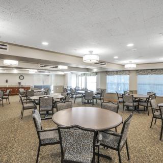 A spacious dining area featuring multiple tables and chairs, with ample lighting and carpeted floors.