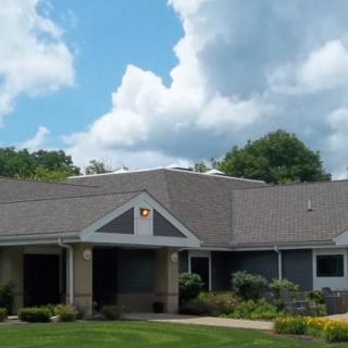 A suburban house with a well-maintained lawn and cloudy sky backdrop.