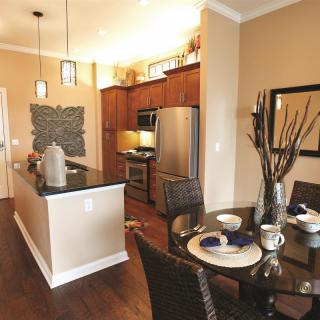 A modern kitchen and dining area featuring stainless steel appliances and wood flooring.