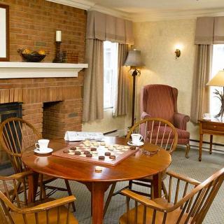 A cozy living room with a brick fireplace, wooden furniture, and a board game set up on the table.