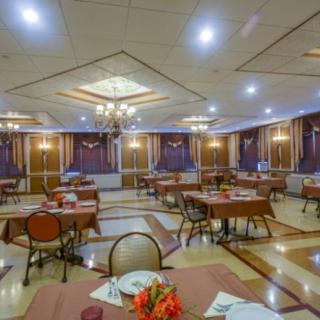 A spacious banquet hall with elegantly set tables and decorative chandeliers.