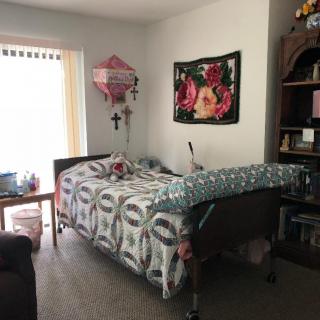 A bedroom with a hospital bed, decorated with floral patterns and a pink balloon.