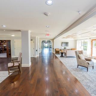 A bright and spacious hallway with wood flooring and comfortable seating areas.