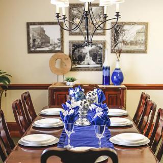 A beautifully arranged dining table with blue accents and elegant decor under a classic chandelier.