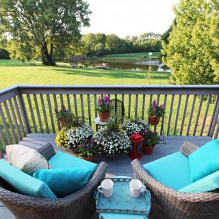 A cozy patio with wicker chairs and colorful cushions overlooking a lush garden.