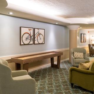 A cozy living room with comfortable seating, a shuffleboard table, and bicycle artwork on the wall.