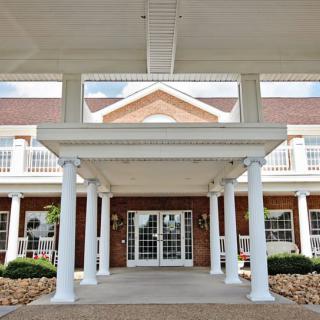 A view of a building entrance featuring white columns and a covered walkway.