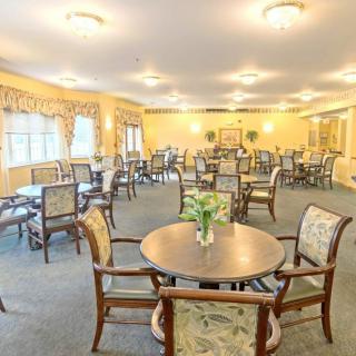A well-lit dining room with multiple tables and chairs, decorated in warm tones.