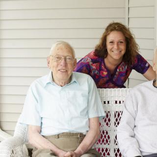 A group of people sitting on a porch, enjoying time together.