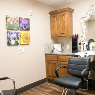 A cozy hair salon interior featuring a styling chair, mirror, and wooden cabinets.