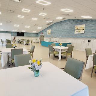 A spacious and modern dining area set up for an event, featuring neatly arranged tables and chairs.