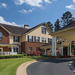 A large residential building with brick and siding exterior, surrounded by well-maintained landscaping and a curving driveway.