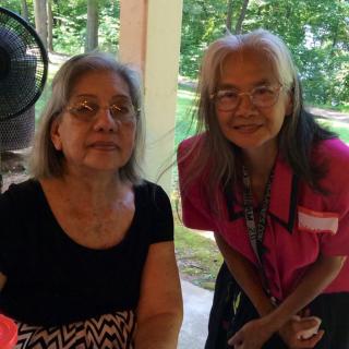 Two women posing together outdoors in a park.