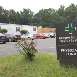 A view of the Greene County Health System's physician clinic, featuring mobile units and a parking area.