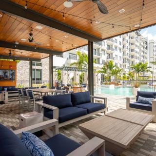 A modern outdoor patio area with comfortable furniture and a view of the pool in an apartment complex.