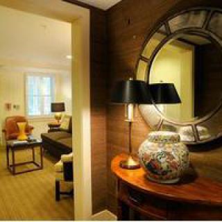 A cozy living room interior featuring a decorative mirror, lamp, and ceramic vase on a wooden table.