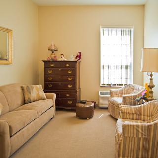 A cozy living room with a sofa, armchairs, and a cabinet.