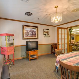 A cozy living room with a television, popcorn machine, and dining table under a chandelier.
