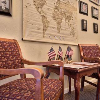 A cozy waiting area with wooden chairs, small American flags, and a vintage world map on the wall.