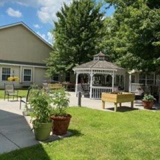 A peaceful outdoor area featuring a gazebo, surrounded by greenery and a well-kept garden.