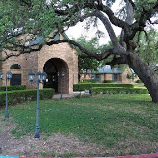 A charming building surrounded by lush greenery and mature trees.