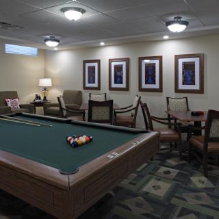 A cozy game room featuring a pool table, comfortable seating, and framed artwork on the walls.