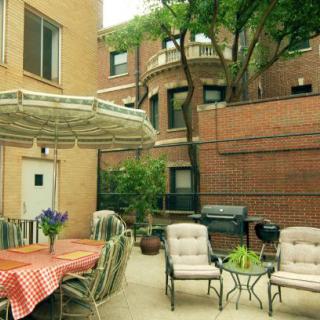 A cozy patio area with a table, chairs, and umbrella set against a brick building backdrop.