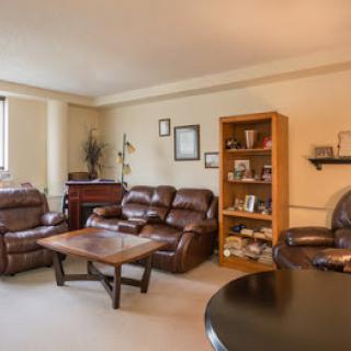 A cozy living room with leather sofas, a wooden coffee table, and a bookshelf.