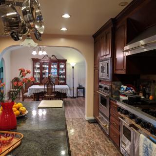 A traditional kitchen opens into a dining room, featuring wood cabinets and stainless steel appliances.