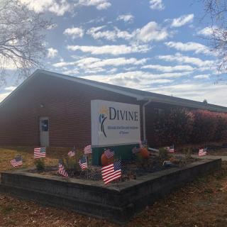 A building with a welcoming sign surrounded by American flags and under a cloudy sky.