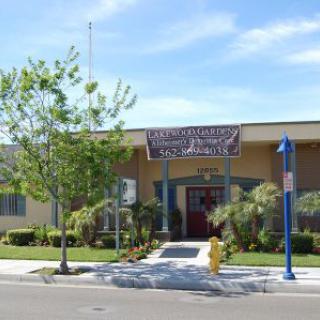 A school building with a banner above the entrance, surrounded by trees on a sunny day.