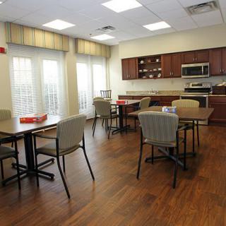 A modern dining area with tables and chairs adjacent to a kitchen.