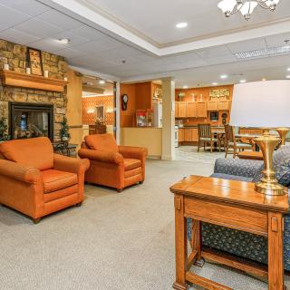 A cozy living room with orange armchairs, a fireplace, and warm lighting.
