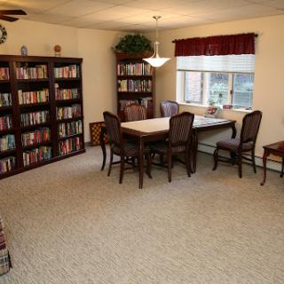 A cozy and well-lit interior space featuring bookshelves, a dining table, and comfortable seating.