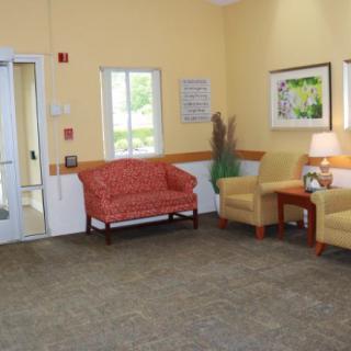 A cozy waiting room with a sofa, chairs, and a table under soft lighting.