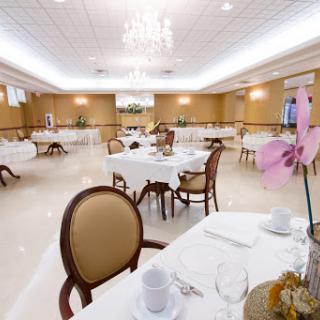An elegantly arranged dining room featuring tables with white tablecloths and beautifully decorated chairs.