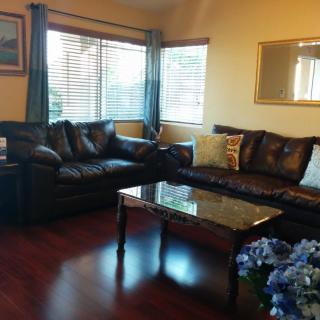 A cozy living room with leather sofas, a coffee table, and large windows.