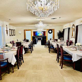 An elegant dining room setup featuring beautifully arranged tables and a stunning chandelier.