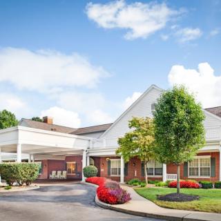 A well-maintained building with landscaped surroundings and a driveway under a cloudy sky.