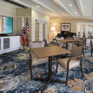 A well-furnished lounge area featuring tables, chairs, flags, and a piano.