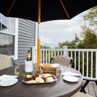 A cozy outdoor patio setting with a table under an umbrella, featuring champagne and a cheese platter.