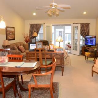 A cozy living room with a combined dining area, featuring comfortable seating, a television, and warm lighting.