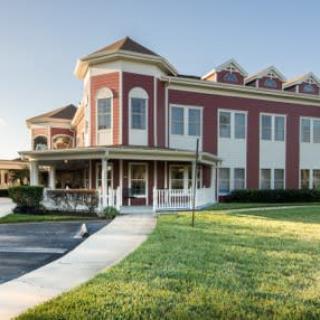 A commercial building with a red and white exterior and manicured lawn under a clear blue sky.